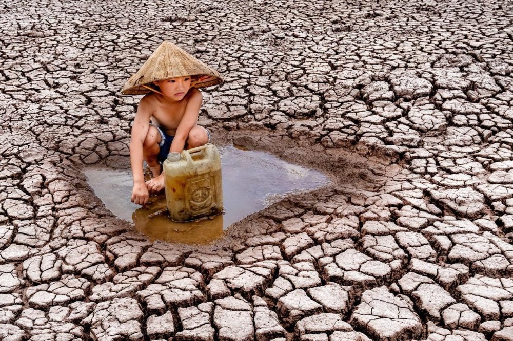 FOTO // Secetă cruntă în Vietnam. Imagini sfâşietoare cu un copil ce strânge ultimele picături de apă dintr-un lac secat pentru a le duce familiei