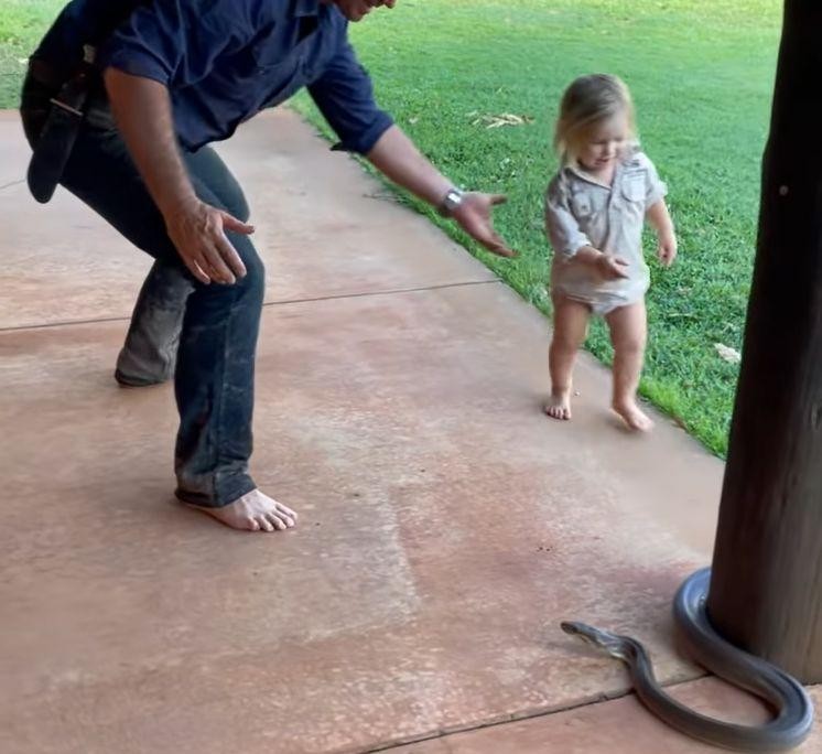 FOTO/VIDEO: Un copil de 2 ani a fost filmat în timp ce trăgea un piton de coadă, sub privirile tatălui